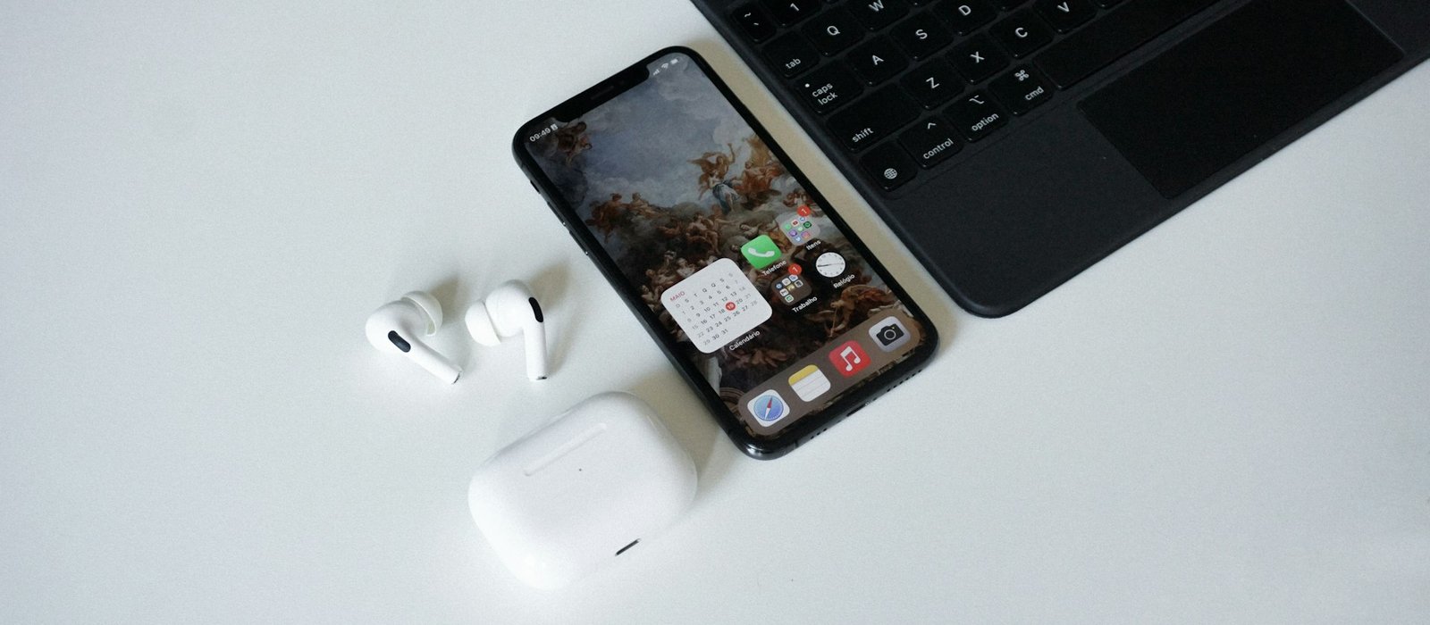Smartphone, earbuds and laptop on white desk